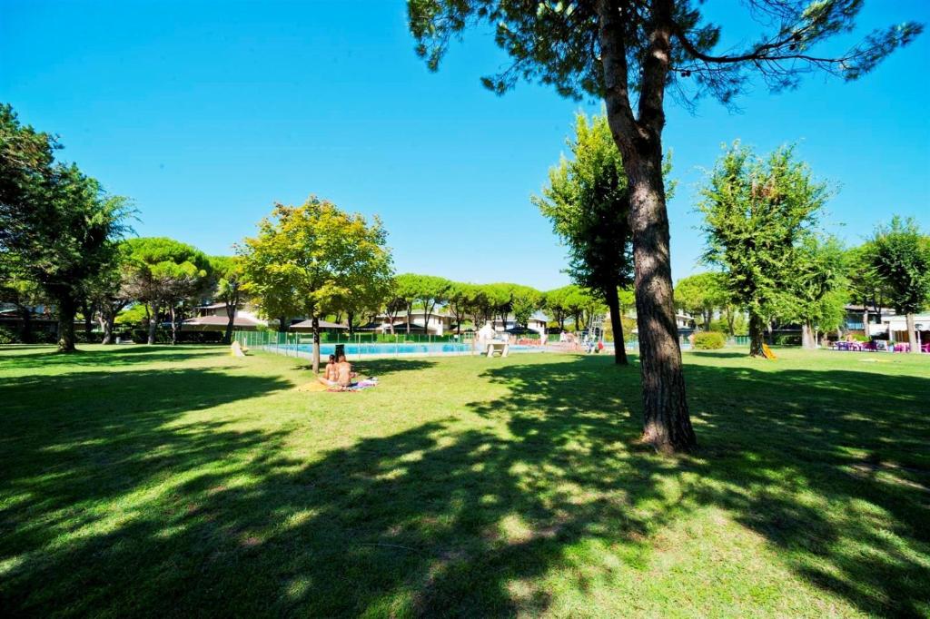 una persona sentada en un parque junto a un árbol en Holiday home in Bibione 24575 en Bibione