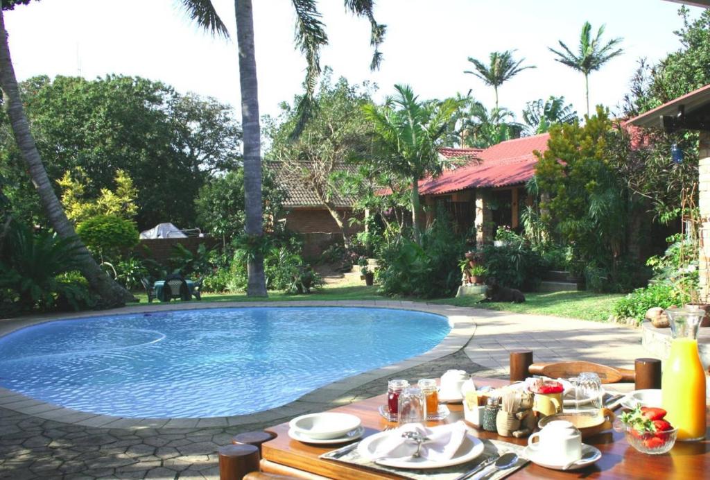 una mesa con comida junto a la piscina en Maputaland Guest House en St Lucia