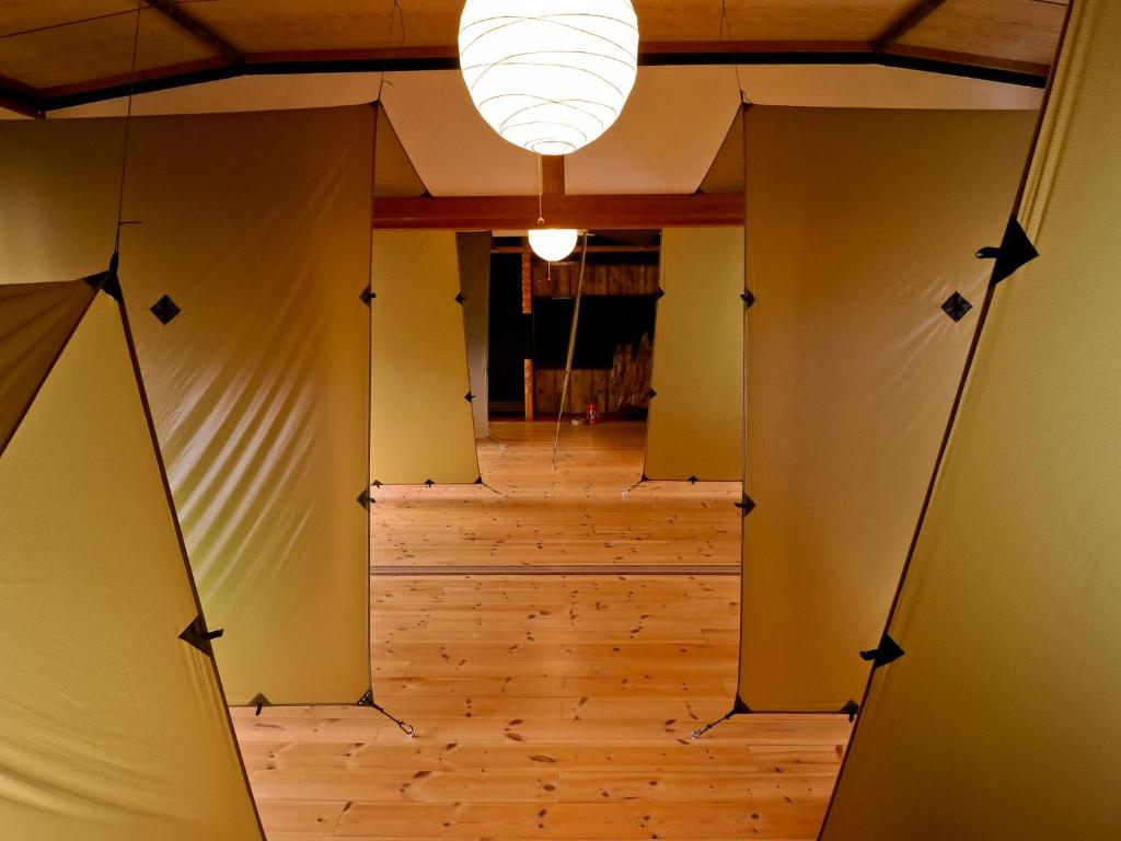 a hallway with wooden floors and a chandelier at Inn the Camp in Kasaoka