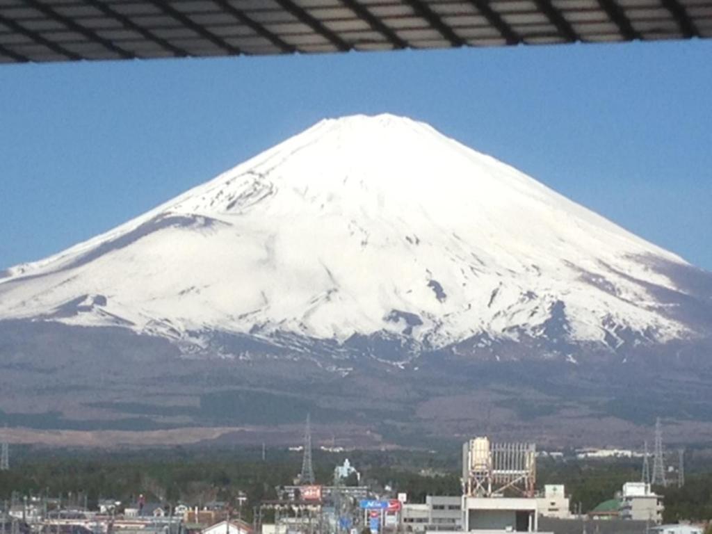 a snow covered mountain in front of a city at Fuji Gotemba Condominium Tannpopo in Gotemba