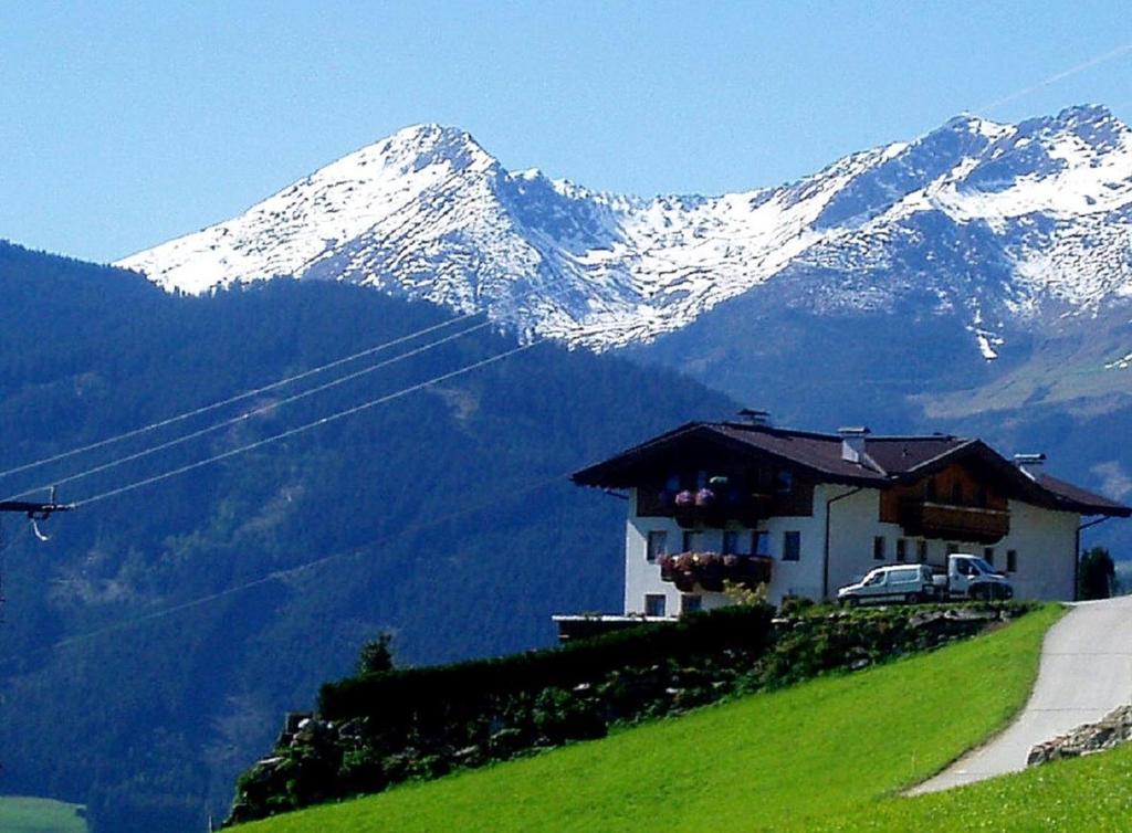 ein Haus auf einem Hügel mit einem schneebedeckten Berg in der Unterkunft Apartments in Stummerberg/Zillertal 773 in Acham