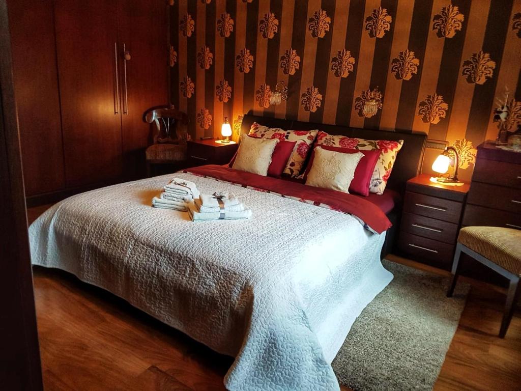 a bedroom with a large bed with red and white sheets at Apartment President in Zagreb