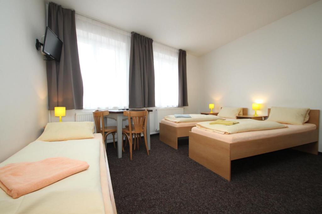 a hotel room with two beds and a table at Apartmány U Gigantu in Plzeň