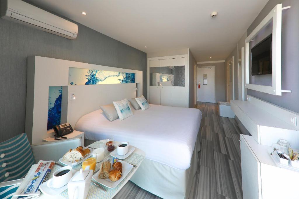 a hotel room with a bed and a table with food at Hôtel Josse in Antibes