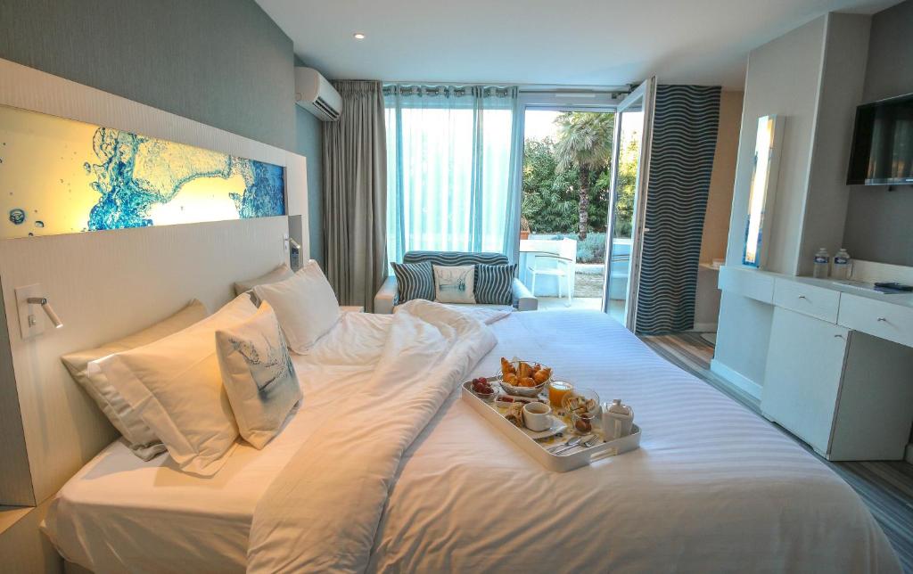a bedroom with a white bed with a tray of food on it at Hôtel Josse in Antibes