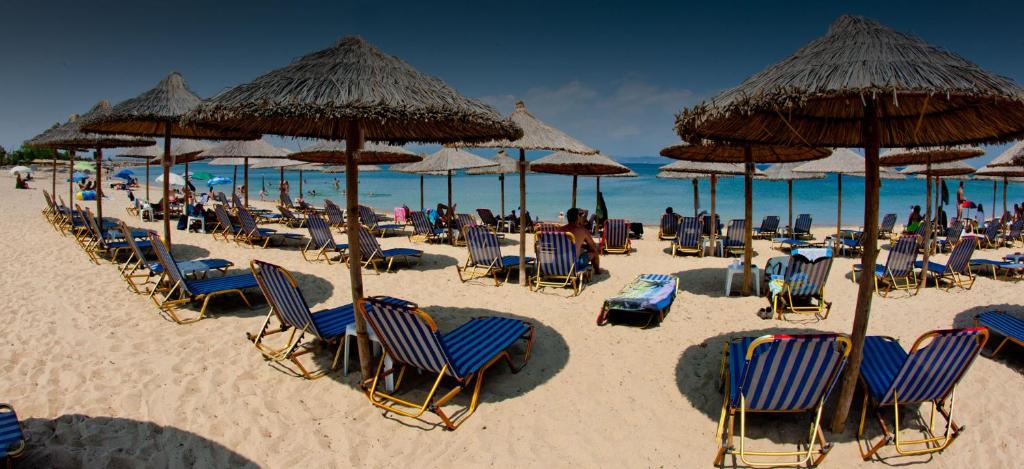 a sandy beach with chairs and umbrellas and the ocean at Golden Beach Potidea in Nea Potidaea