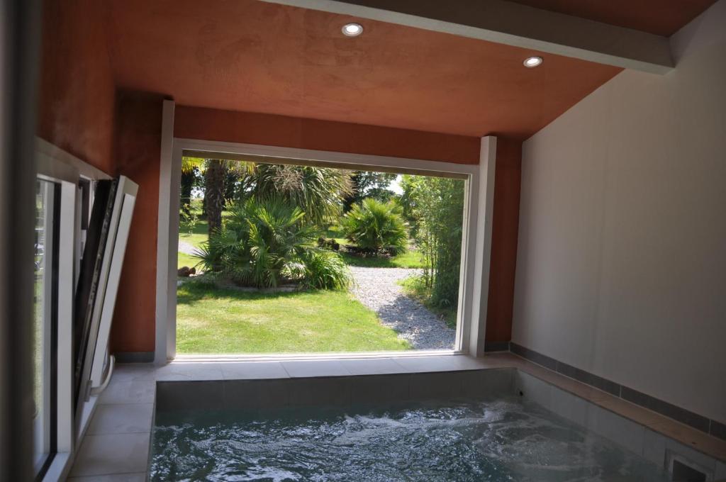 een kamer met een bad en een groot raam bij Le Domaine Des Grettes in La Dominelais