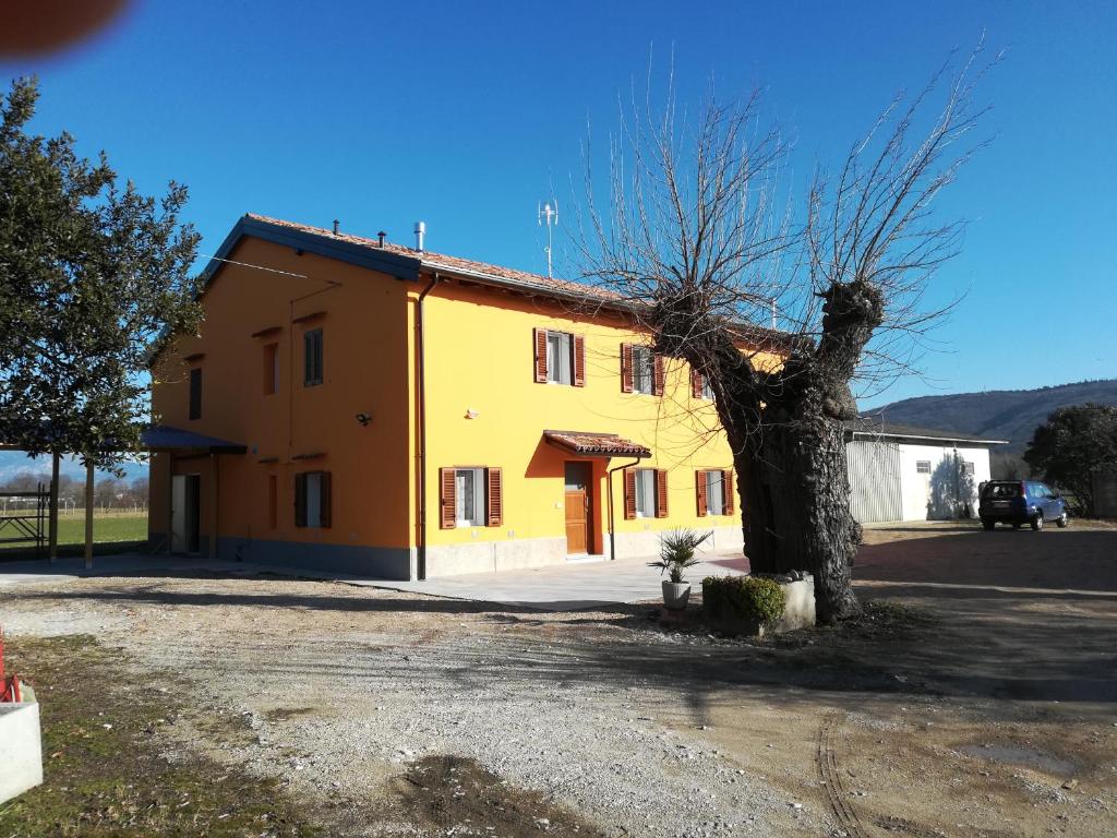 una casa gialla con un albero di fronte di AL MORAR a Farra dʼlsonzo