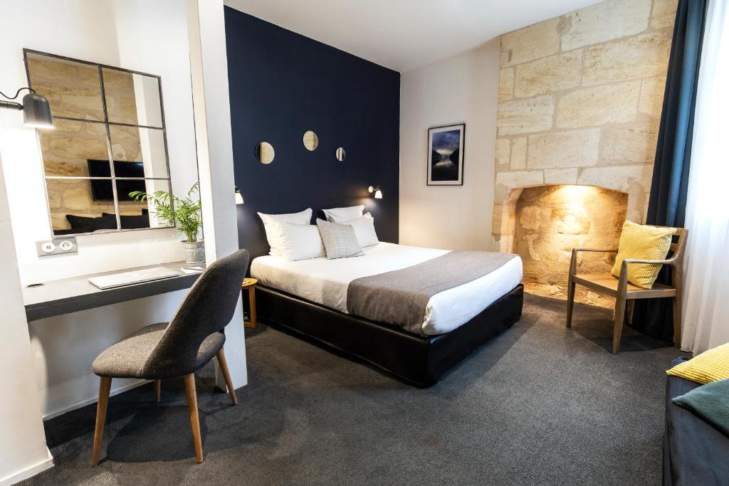 ボルドーにあるHôtel La Cour Carrée Bordeaux Centreのベッド、デスク、椅子が備わるホテルルームです。