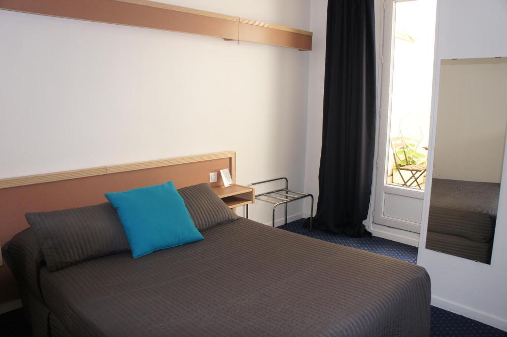 Un dormitorio con una cama con una almohada azul encima. en Hôtel Edgar Quinet, en París