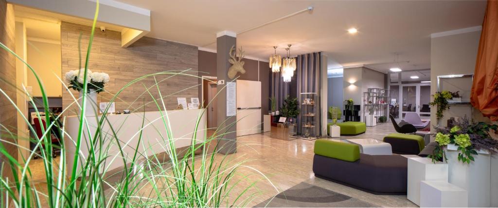 a lobby with green and white furniture and plants at Hotel Alla Fonte in Arta Terme