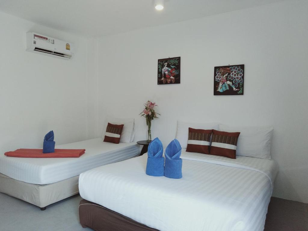 2 Betten in einem Zimmer mit blauen Schuhen darauf in der Unterkunft Pink Easy Homes Koh Phangan in Thongsala