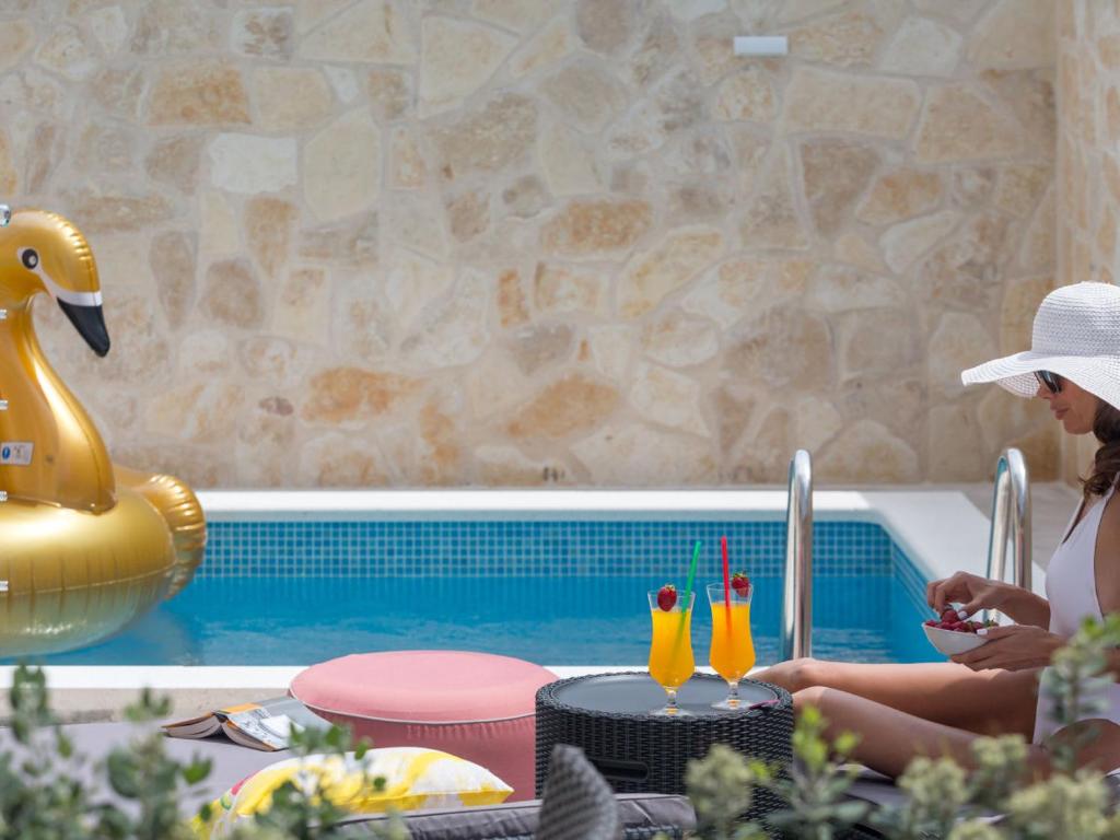 uma mulher de chapéu sentada ao lado de uma piscina em Apartment Villa Franko Maris em Podstrana
