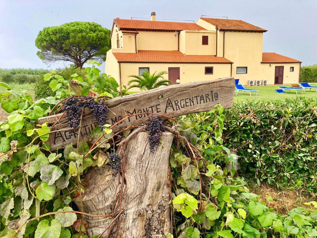 a sign on a tree stump in front of a house at Agriturismo Ristorante Monte Argentario in Monte Argentario