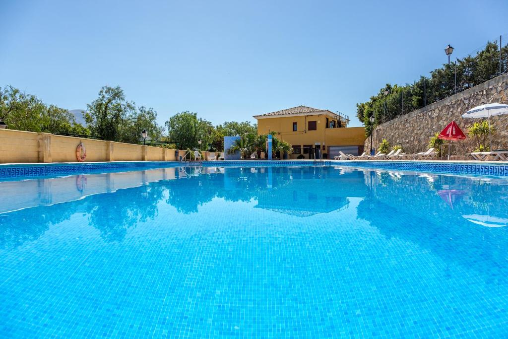 a large swimming pool with blue water at Camping Rural Presa La Viñuela in Viñuela