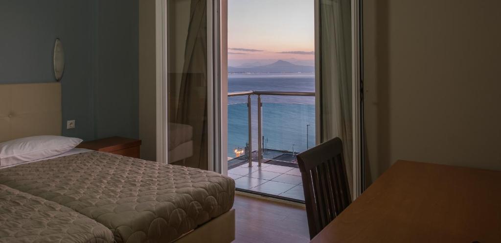 a bedroom with a bed and a view of the ocean at Grand Olympic Hotel Loutraki in Loutraki