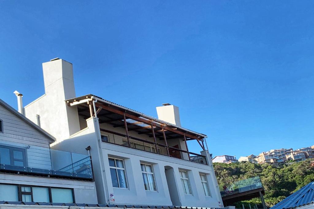 a white building with a balcony on top of it at Toms Cabin in Herolds Bay