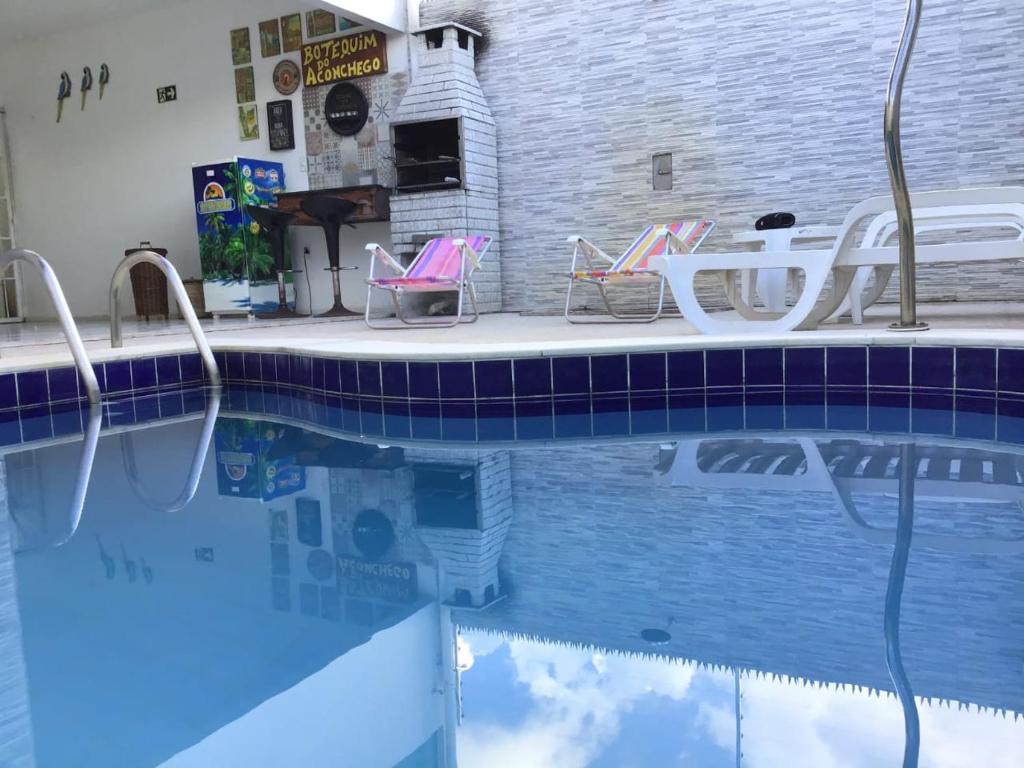 a swimming pool with two chairs and a table and water at Aconchego dos Milagres in São Miguel dos Milagres