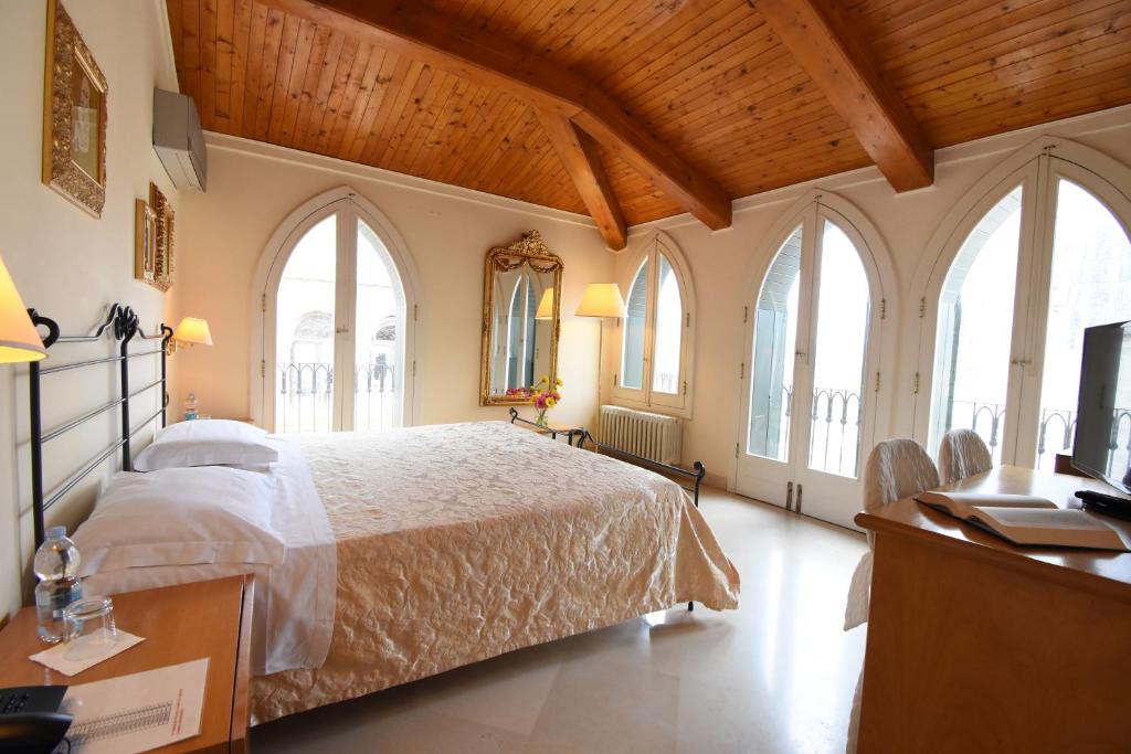 una camera con un grande letto e finestre di Palazzo Sottile Meninni a Gravina in Puglia