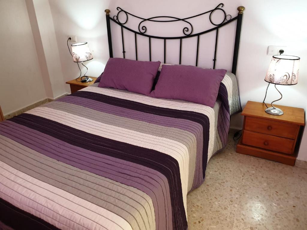 1 dormitorio con 1 cama grande con almohadas moradas en Hostal Gutierrez, en Ceuta