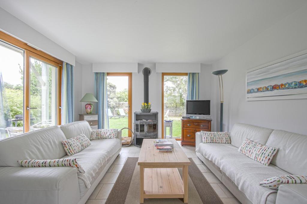 a living room with white couches and a coffee table at Les Costils in Saint-Laurent-sur-Mer