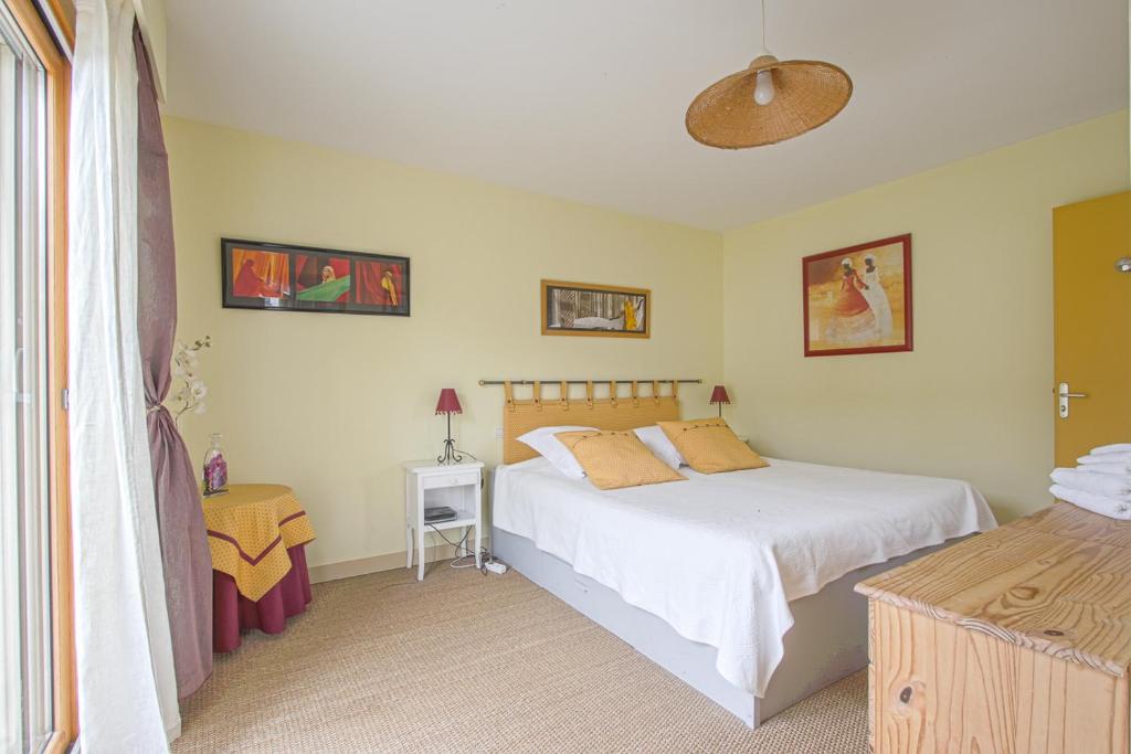 a bedroom with a white bed and a window at Les Costils in Saint-Laurent-sur-Mer