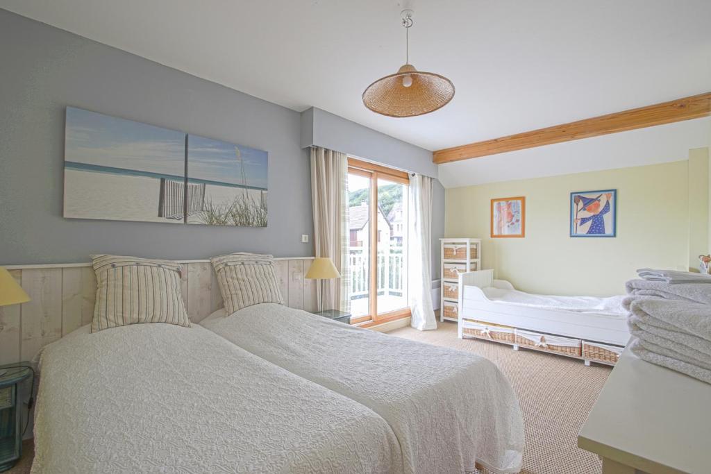 a bedroom with a white bed and a window at Les Costils in Saint-Laurent-sur-Mer
