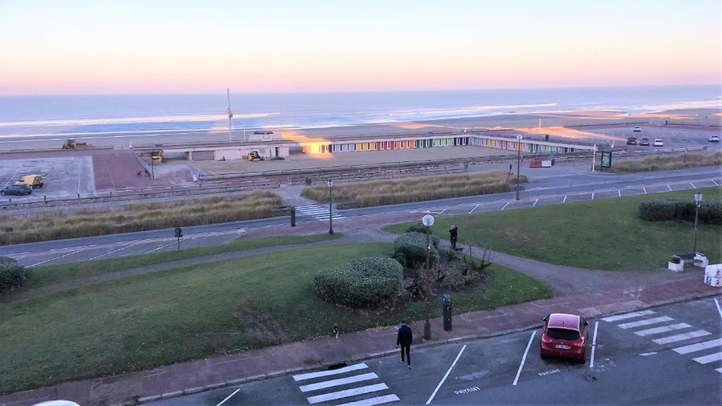 un estacionamiento con un coche rojo delante de un edificio en SPLENDIDE T3 DE 70m2 VUE MER A 2 MINUTES DU CENTRE-VILLE en Le Touquet-Paris-Plage