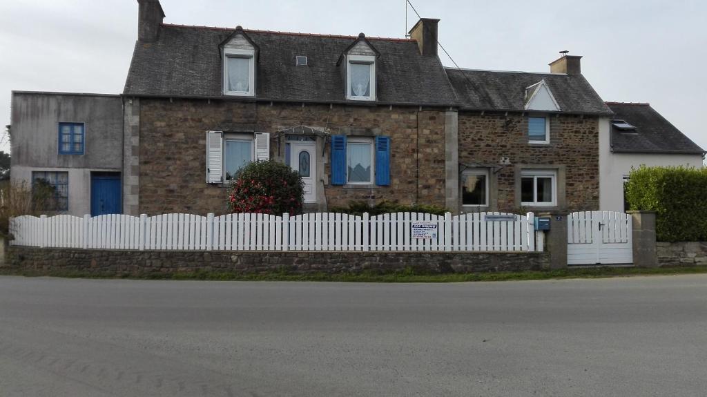 une maison en briques avec une clôture blanche dans l'établissement maison yvonne, à Plouha