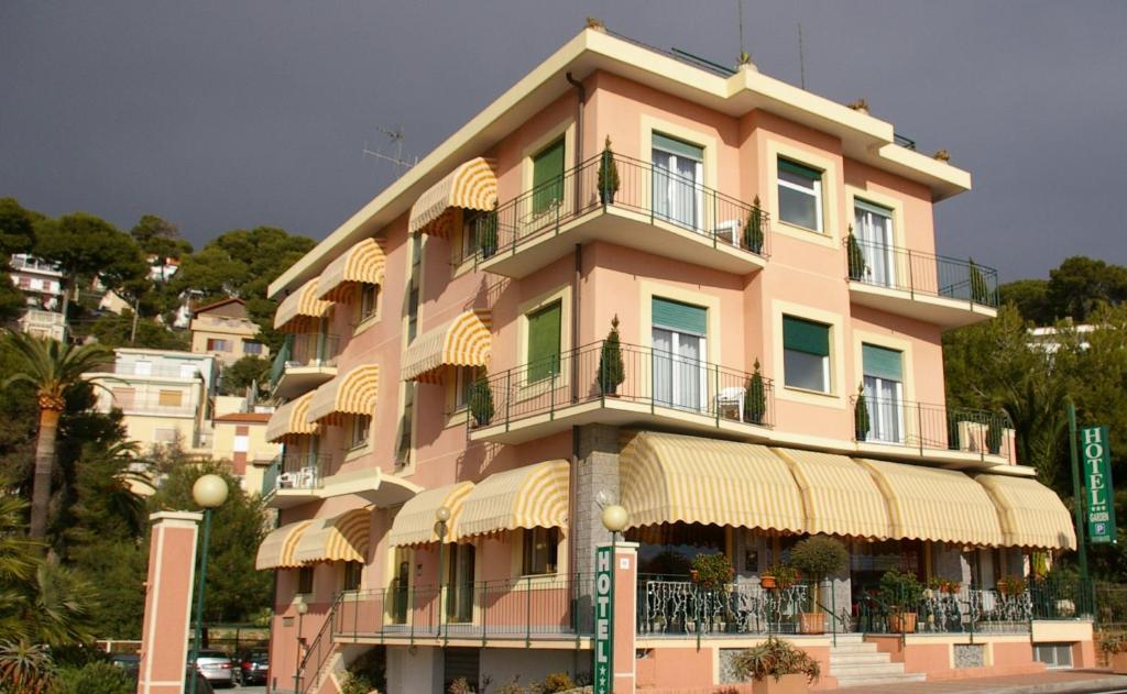 ein großes rosafarbenes Gebäude mit Balkon auf einer Straße in der Unterkunft Hotel Garden in Marina dʼAndora