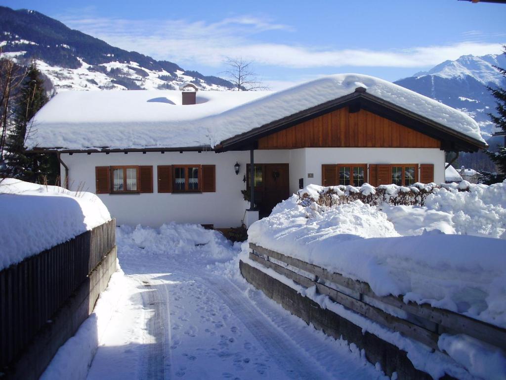 une maison recouverte de neige devant une maison dans l'établissement Montafon Alpen Chalet, à Vandans