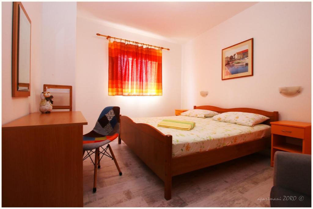 a bedroom with a bed and a desk and a window at Apartments Zoro in Primošten