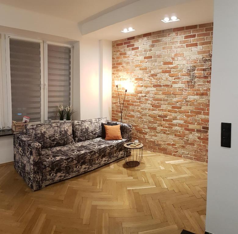 a living room with a couch and a brick wall at Apartamenty Planet in Warsaw