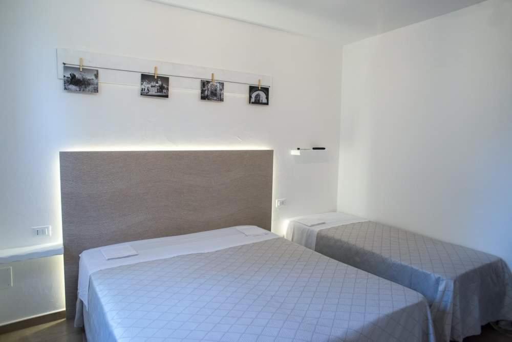 1 dormitorio con 2 camas y 2 cuadros en la pared en Masseria Nzeta, en Carovigno