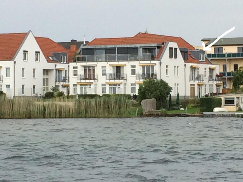 a row of white houses next to a body of water at Residenz Am Seeufer 59a in Waren