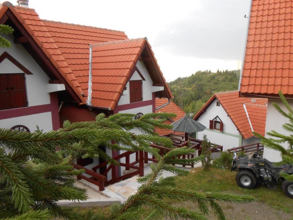 eine Reihe von Häusern mit orangefarbenen Dächern und einem Traktor in der Unterkunft Vile M&S in Kopaonik