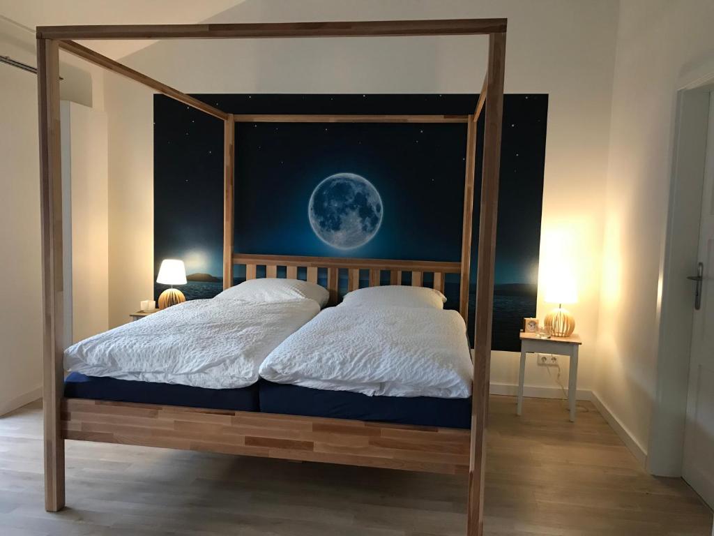 1 dormitorio con cama con dosel y mural de luna en SEASIDE APARTMENTS - BEACHHOUSE SKY, en Eckernförde