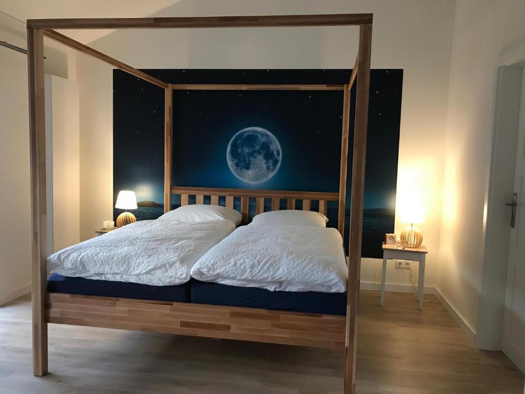 ein Schlafzimmer mit einem Himmelbett und einem Mondbild in der Unterkunft SEASIDE APARTMENTS - BEACHHOUSE SKY in Eckernförde