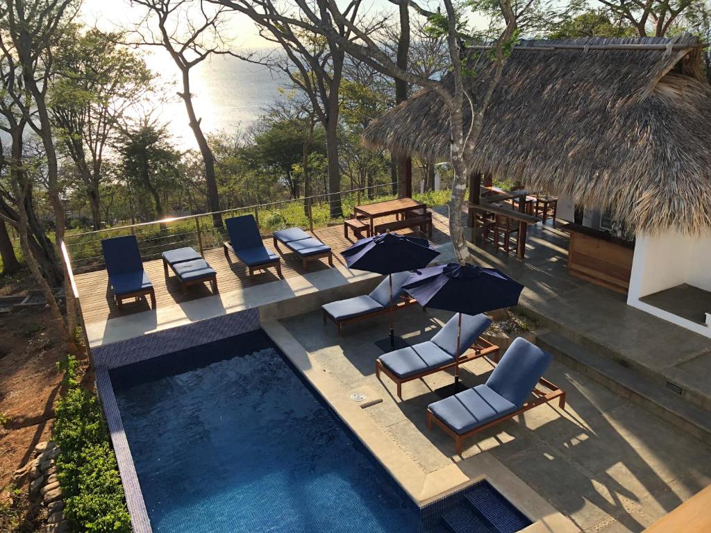 ein Bild eines Swimmingpools mit Stühlen und Sonnenschirmen in der Unterkunft Verdad Nicaragua in San Juan del Sur