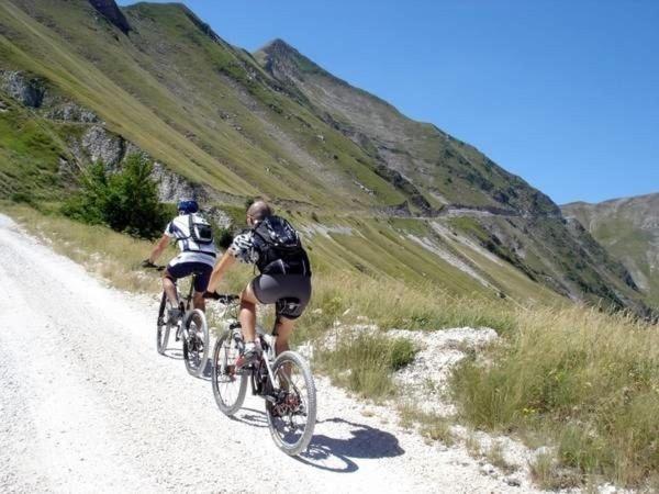 dwoje ludzi jeżdżących rowerami po polnej drodze w obiekcie Agriturismo Castello Di San Vittorino w mieście Gubbio