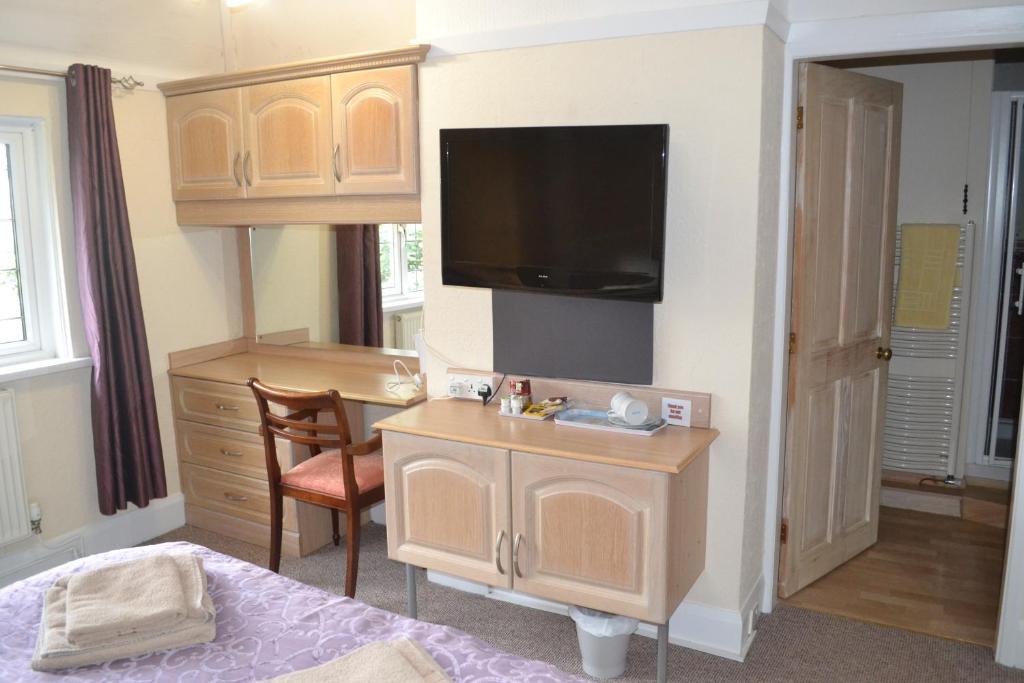 a room with a desk with a tv and a bed at Sunnycroft in Sutton on Sea