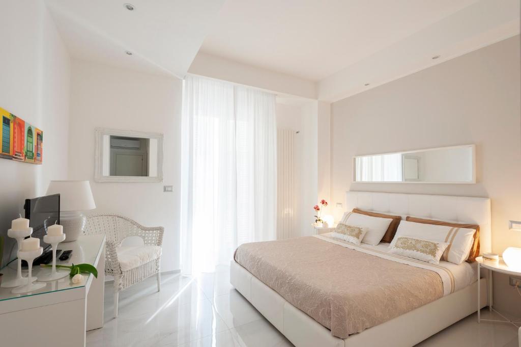 a white bedroom with a bed and a chair at Via Dante Luxury Home in Bari