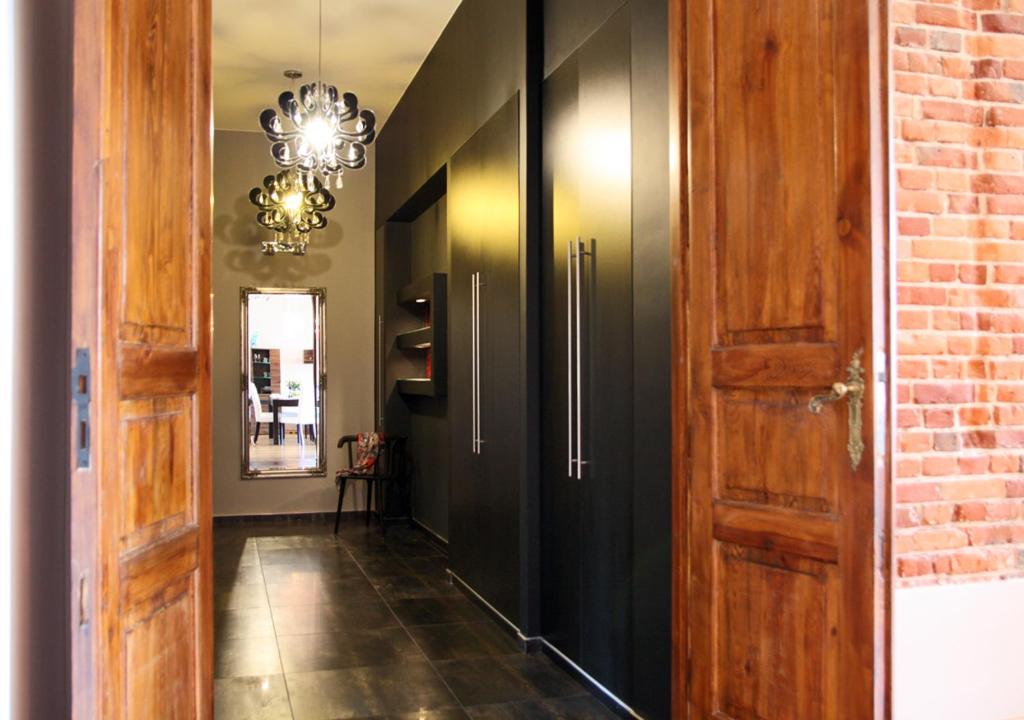 a hallway with black cabinets and a chandelier at Marilyn Apartment in Łódź