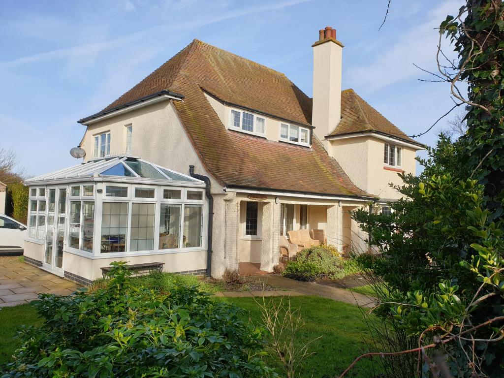 a large white house with a conservatory in the yard at Sunnycroft in Sutton on Sea