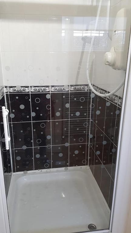 a shower with a black and white tiled wall at Sunnycroft in Sutton on Sea