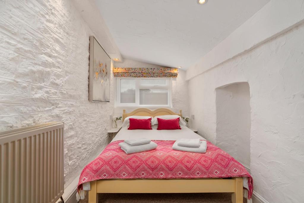 ein Schlafzimmer mit einem großen Bett mit roten Kissen in der Unterkunft Jasmine Cottage in Paignton
