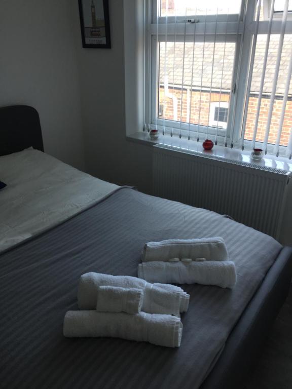 twee handdoeken bovenop een bed met een raam bij Sama's Stylish Room 5 in Manchester