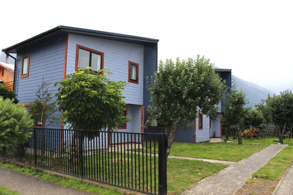 une maison bleue avec une clôture devant elle dans l'établissement Aysén Cabañas, à Puerto Aisén