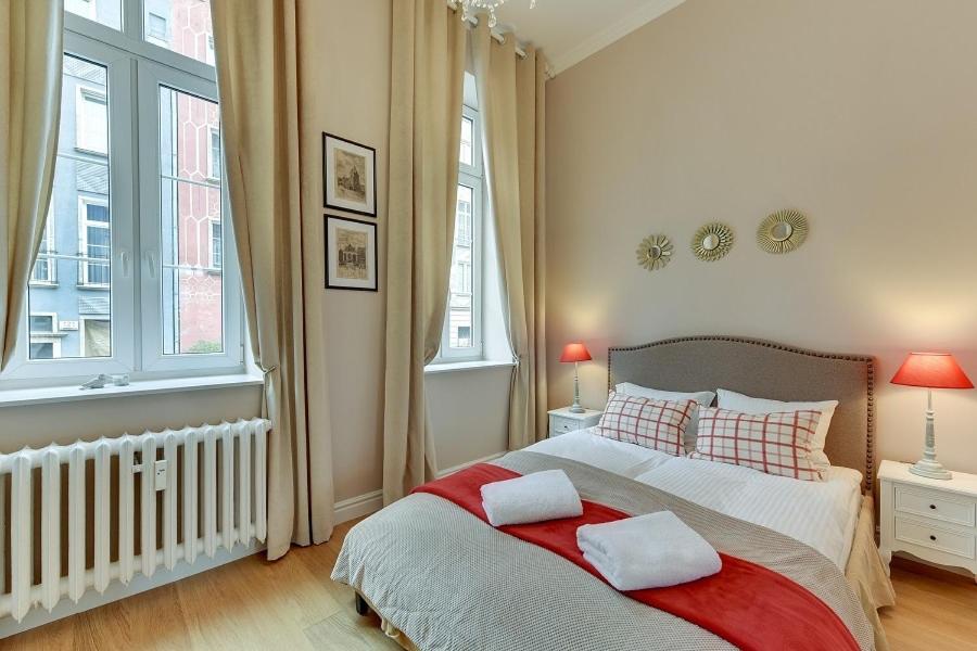 a bedroom with a large bed with two windows at BE IN GDANSK Apartments - IN THE HEART OF THE OLD TOWN - Ogarna 10 in Gdańsk