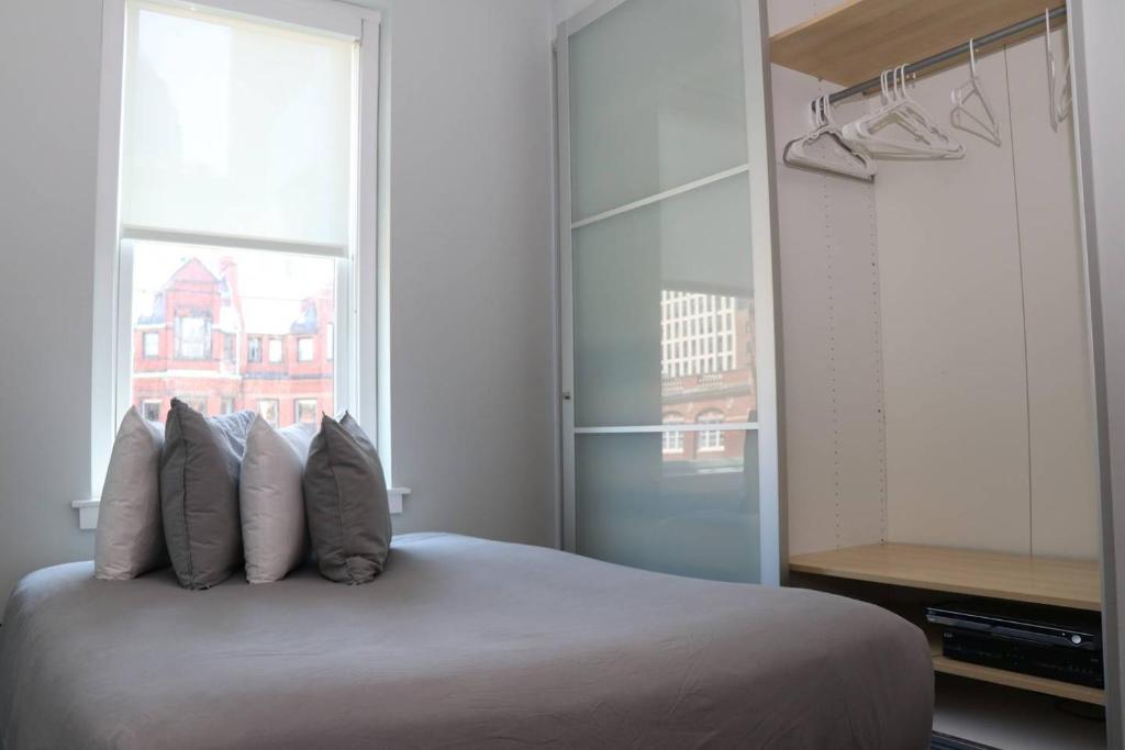 een slaapkamer met een bed met kussens en een raam bij Comfortable Studio in Back Bay, Newbury St. #7 in Boston